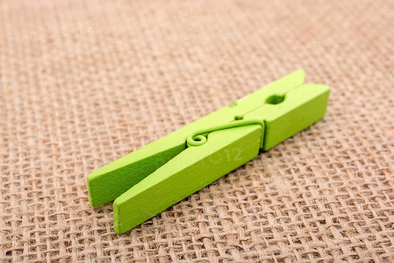 Green wooden clothespin on a textured background on display