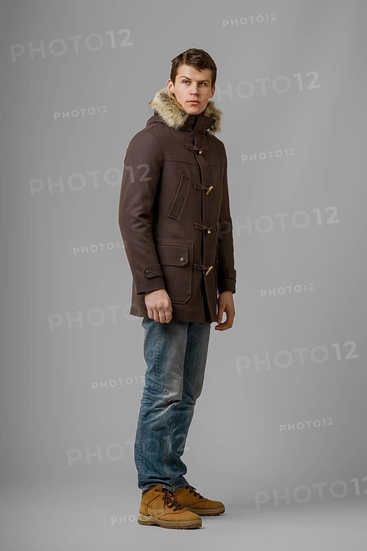 Full length portrait of handsome man in warm woolen coat posing in studio