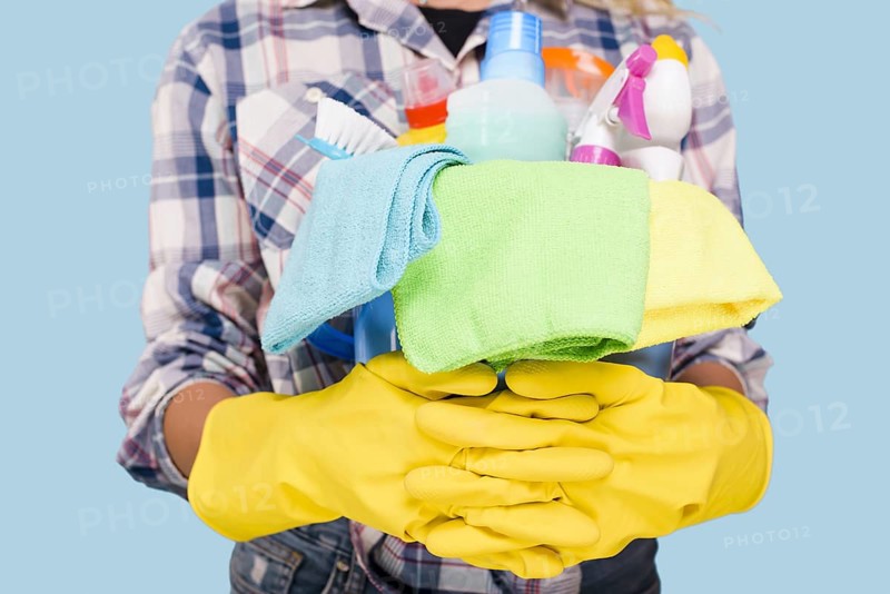 Mid section cleaner holding bucket with cleaning products wearing yellow gloves
