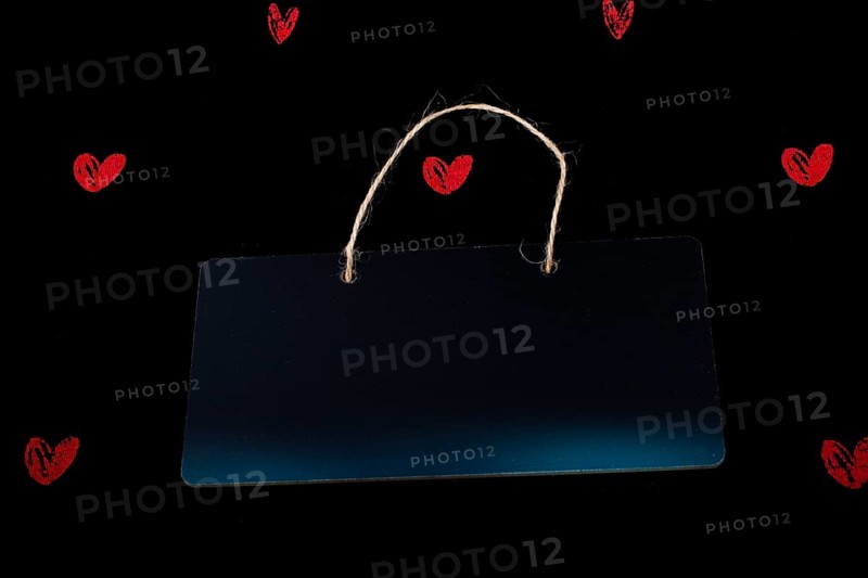 Rectangular shaped black notice board and red hearts on black background