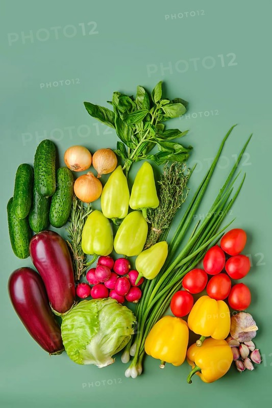 Fresh vegetables scattered on pale green background