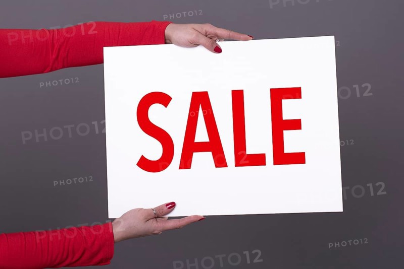 Female hands holding a Sale poster. Studio shot