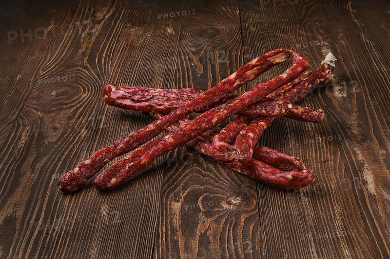 Air dried deer and pork sausage on wooden background
