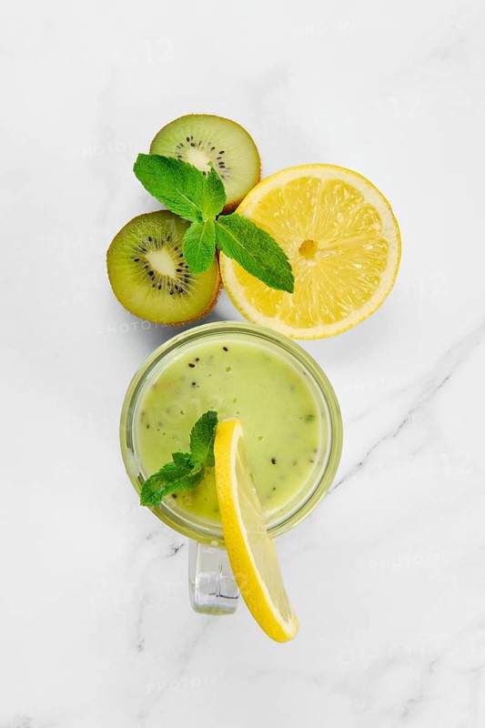 Overhead view of kiwi and lemon smoothie with mint on marble background