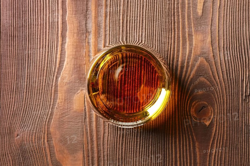 Top view of snifter glass with pure whiskey on dark wooden table