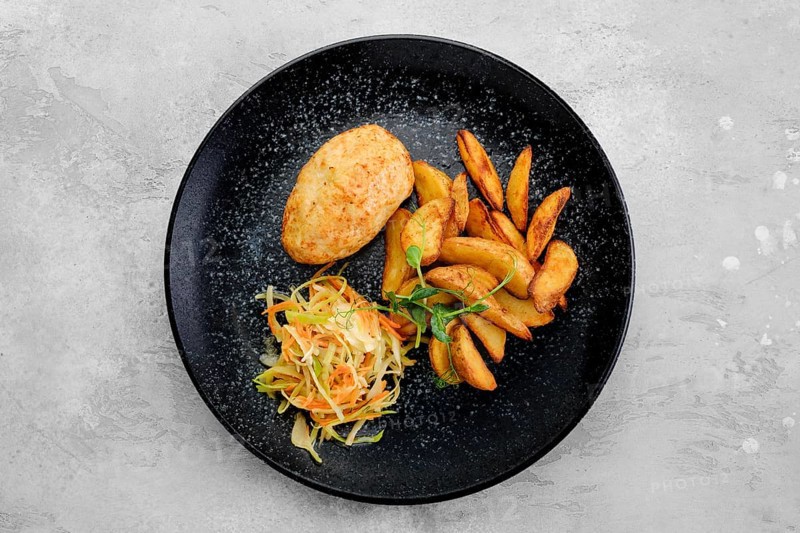 Kiev cutlet stuffed with cheese and butter served with fried potato wedges and pickled cabbage