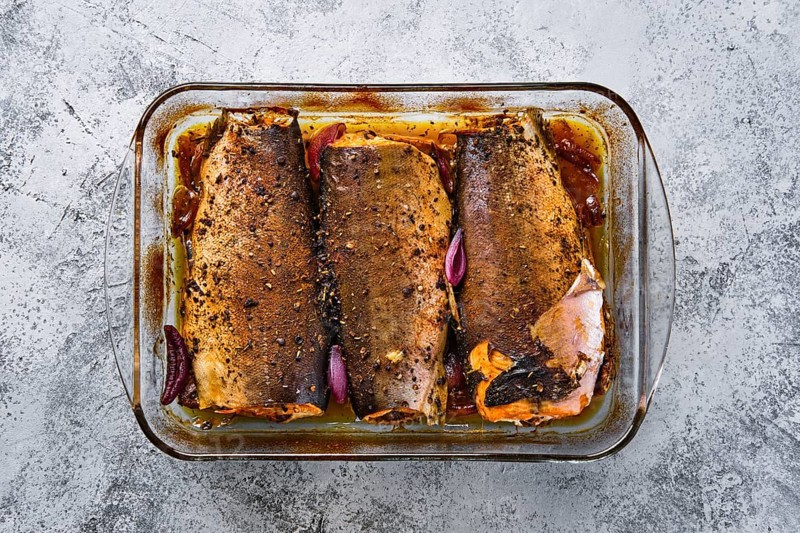 Top view of pan with red salmon baked in oven with spice