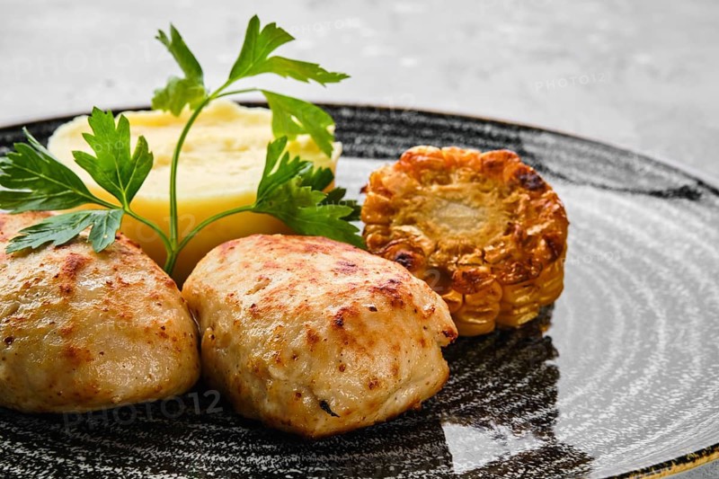 Close up view of ground meat cutlet with mashed potato and grilled corn slices