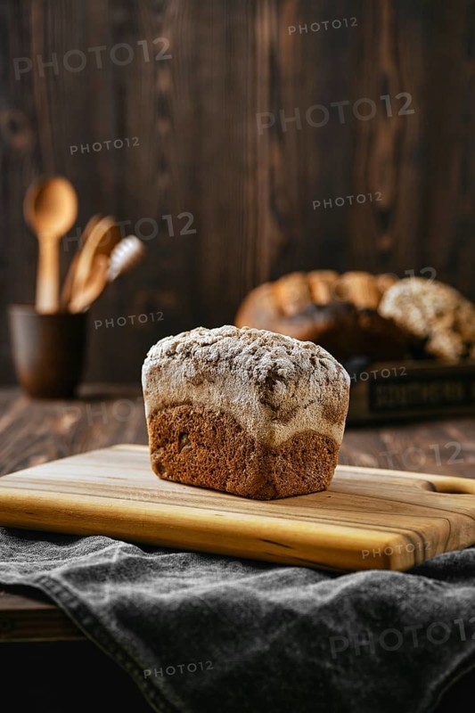 Loaf of artisan rye bread with flour topping on wooden cutting board
