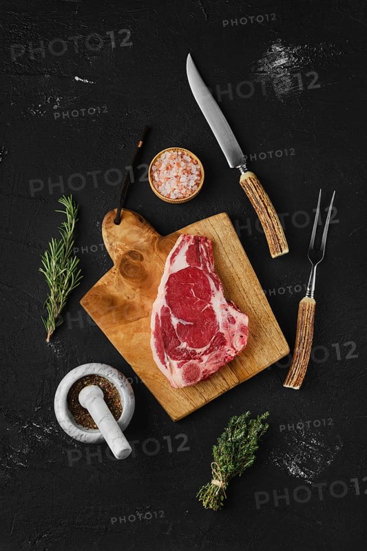 Overhead view of raw strip steak bone in on dark background