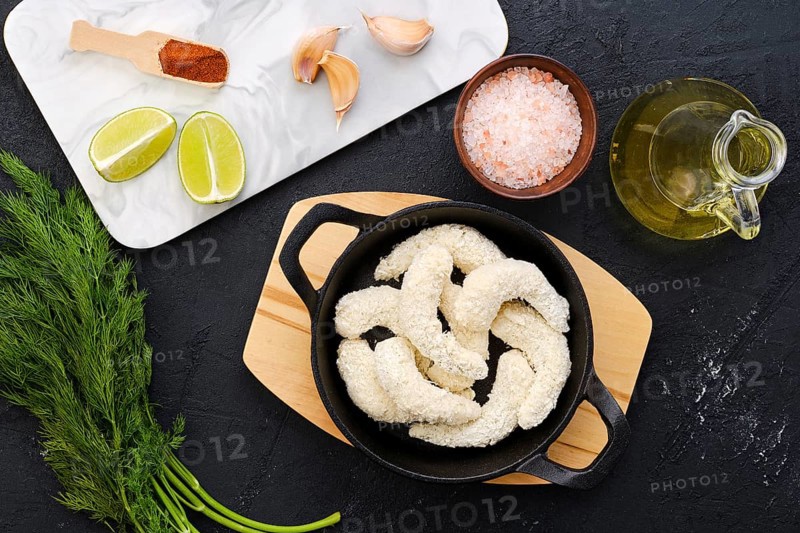 Top view of prepared for frying uncooked shrimps in cheese breading with spice