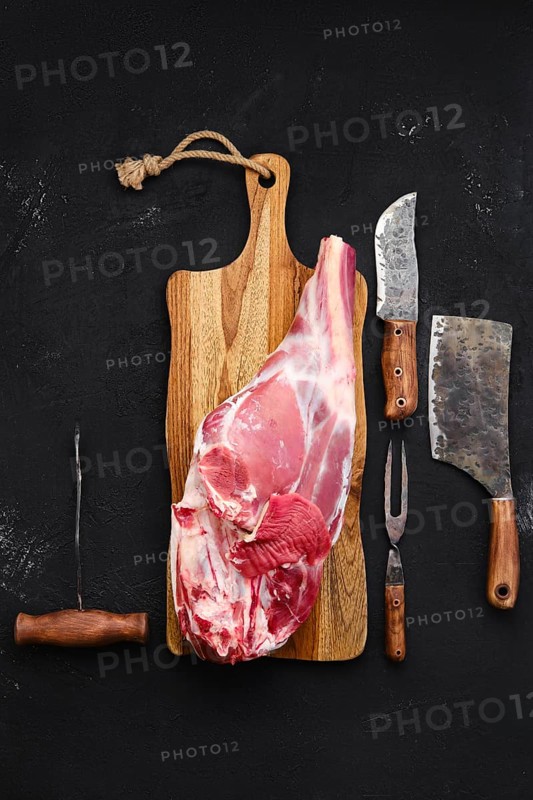 Fresh raw lamb leg bone in on wooden cutting board