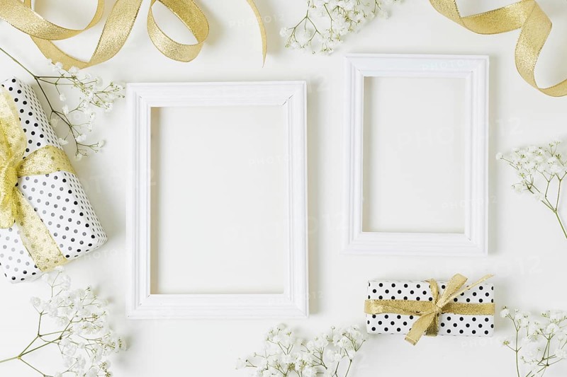 Golden ribbon gift boxes baby s breath flowers near wooden frame white backdrop