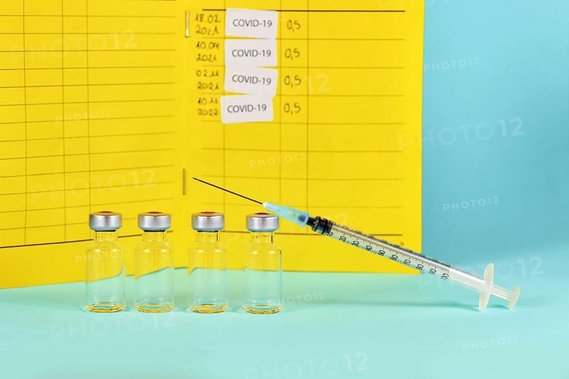Corona booster vaccine concept with 4 vials with syringes and certificate of vaccination in background with copy space