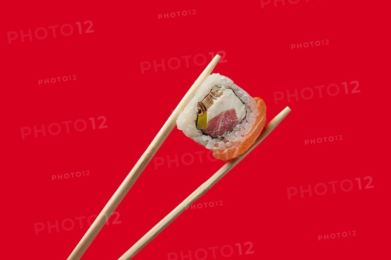 Holding roll with salmon and tuna with chopsticks