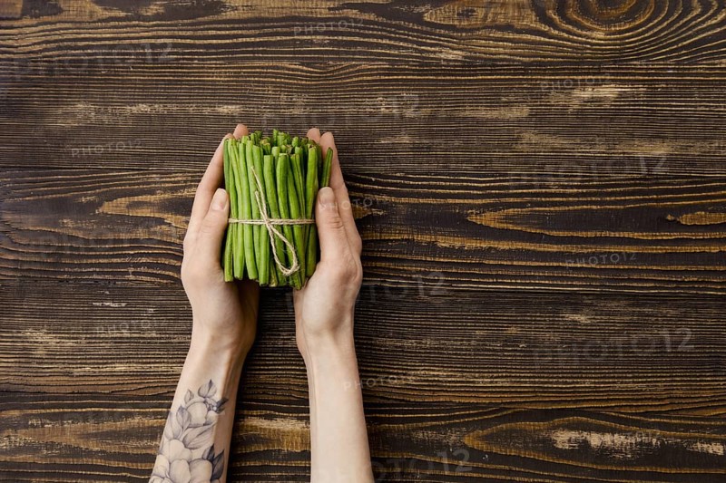 Overhead view of fresh green beans in hand over wooden background