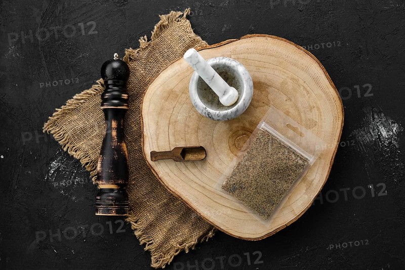Wooden cross section with mustard in plastic package and stone mortar and mill