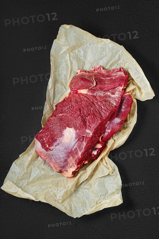 Overhead view of raw fresh beef neck on wrapping paper