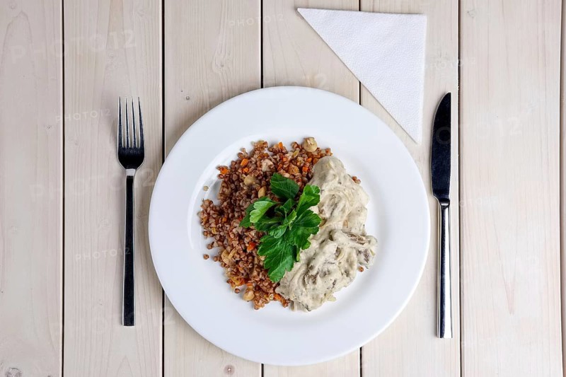 Top view of beef stroganoff with creamy onion sauce and buckwheat with fried mushrooms on served table