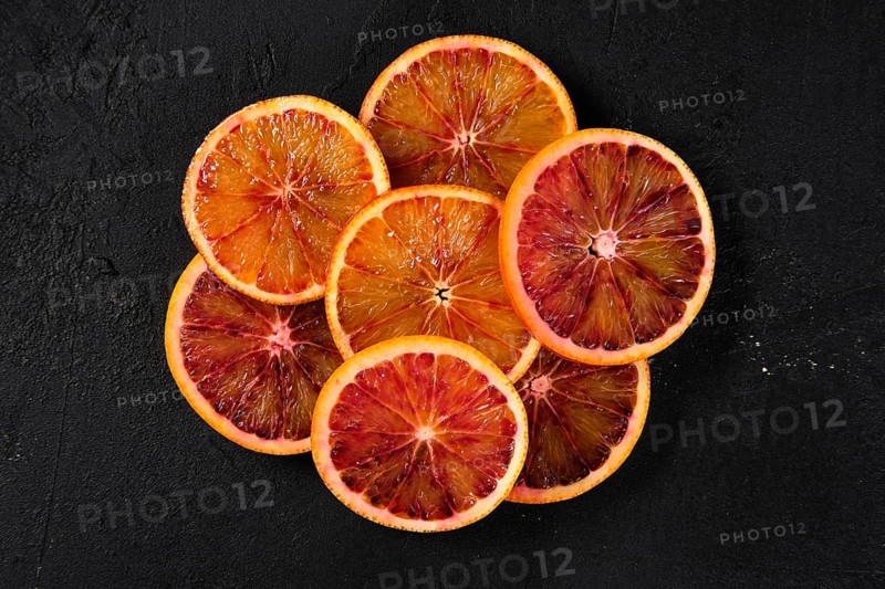 Overhead view of slices of blood orange on black background