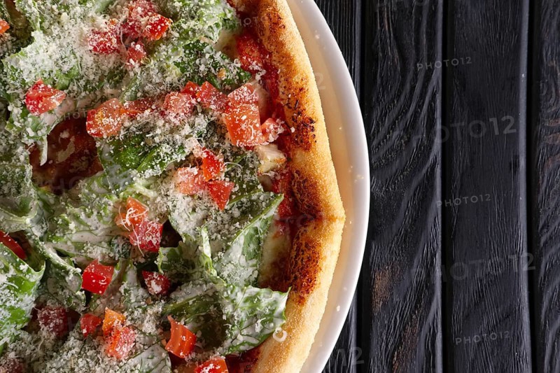 Top view of pizza with ham and green salad leaves arugula