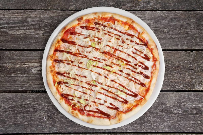 Top view of pizza with chicken barbecue on wooden table