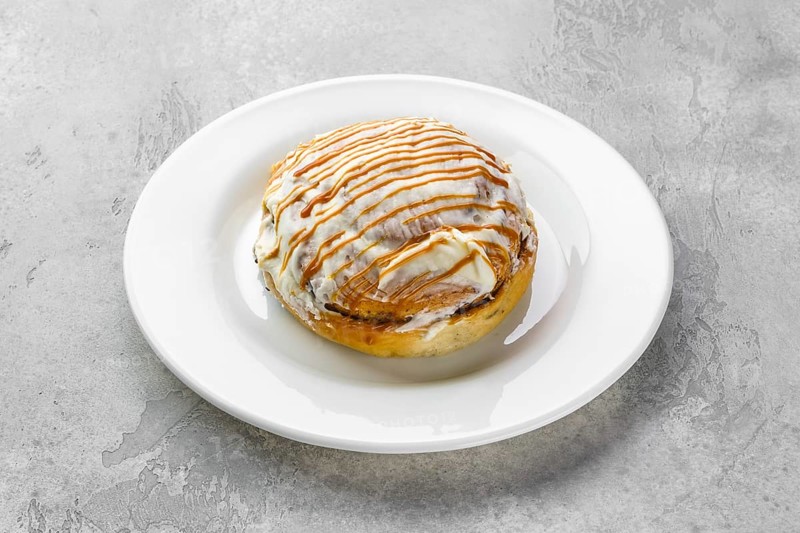 Fresh cinnamon bun with sugar icing and caramel