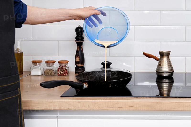 Closeup view of pouring omelet on frying pan