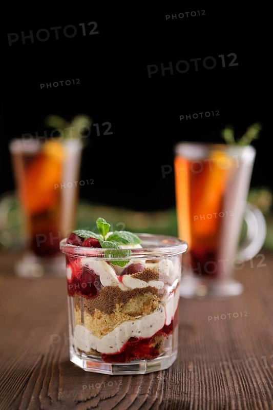Delicious tiramisu dessert with cherry and citrus tea on dark wooden background