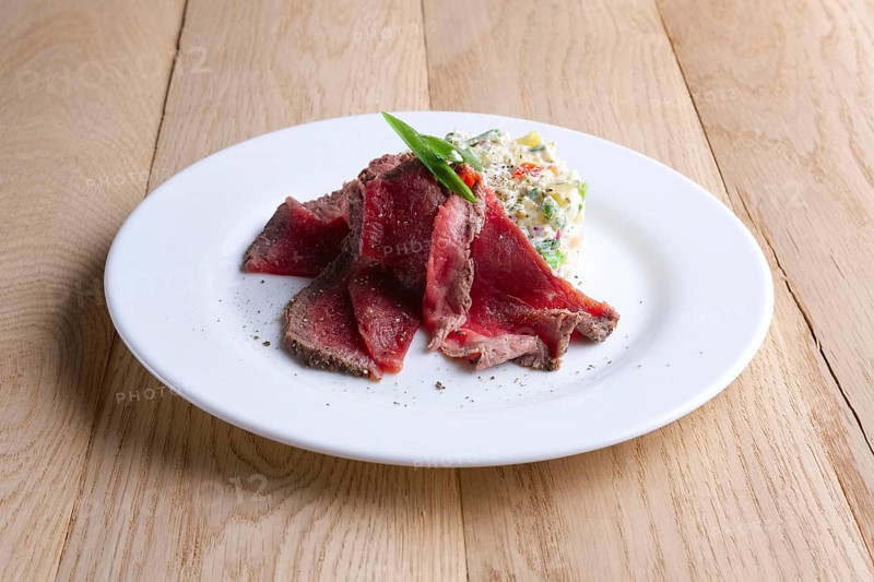 Roasted meat with salad olivier on wooden table