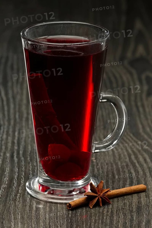 Glass of hot cherry tea with cinnamon on wooden table on dark wooden table