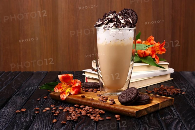 Glass with coffee cocktail with whipped cream and cookie decorated with coffee beans and flowers