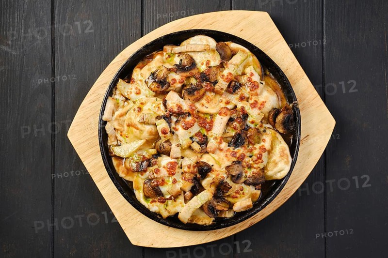 Overhead view of slices of eggplant baked with champignon and cheese in cast iron skillet