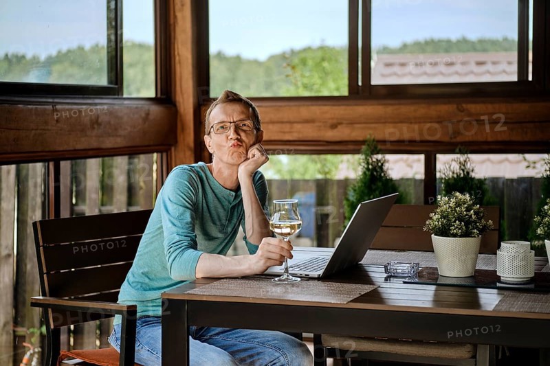 Funny man sits behind the table with laptop
