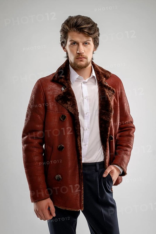 Brutal handsome unshaven man with beard and moustache in sheepskin coat with fur collar