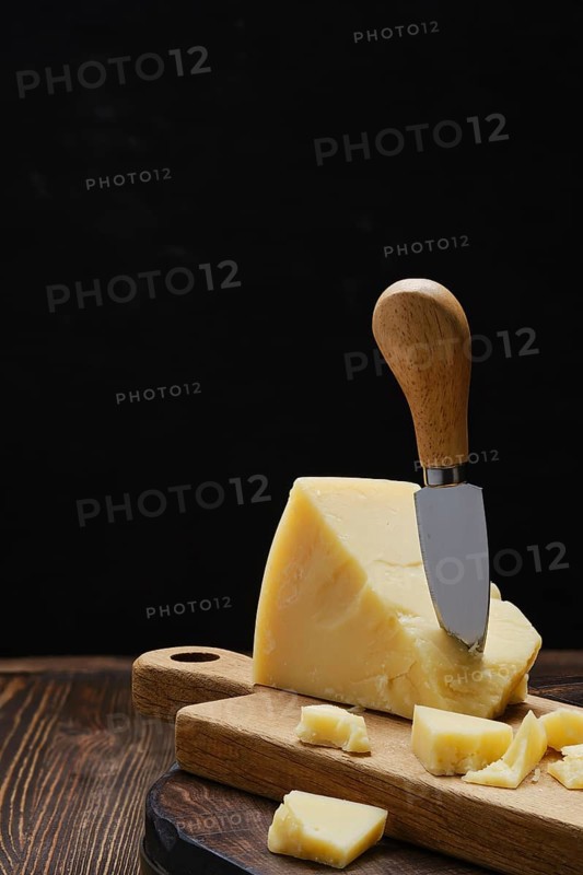 Triangular piece of parmesan cheese on wooden cutting board
