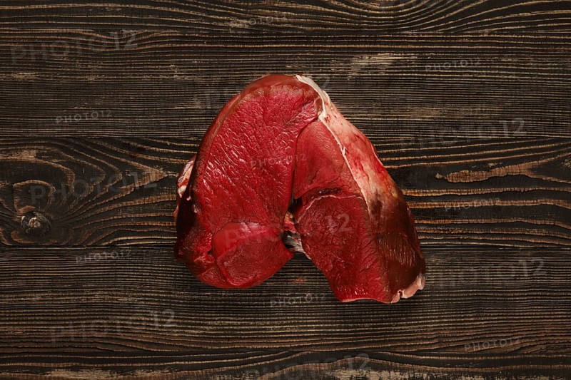 Overhead view of raw deer boneless ham over wooden background