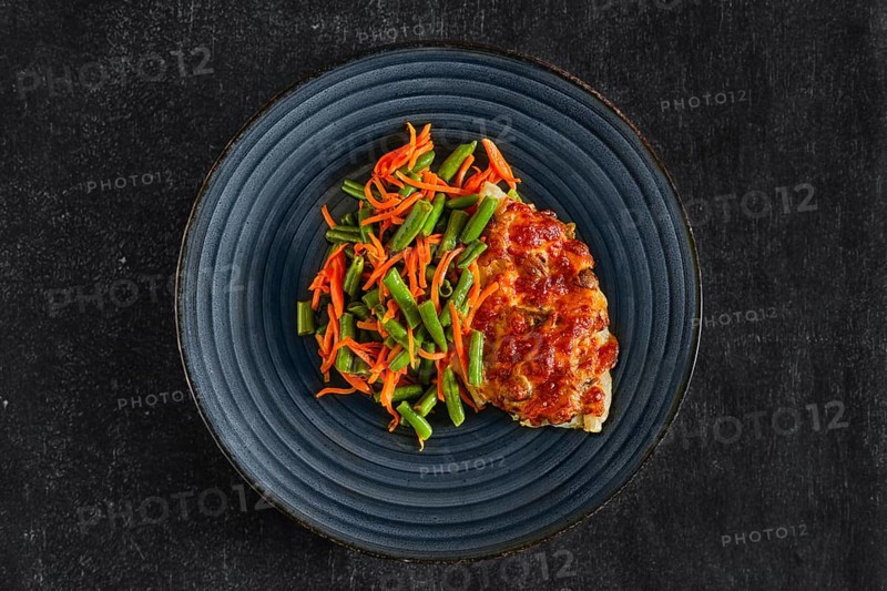 Top view of fried fillet of white fish with cheese topping served with green bean and spicy carrot