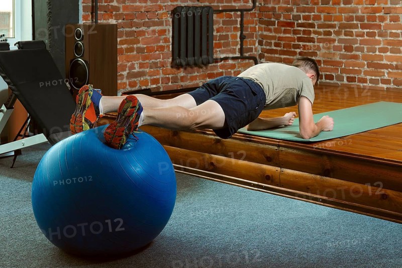 Athletic man doing balancing exercises with the gym ball. Fitness workout