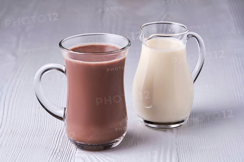 Cup of cappuccino and small creamer on wooden table