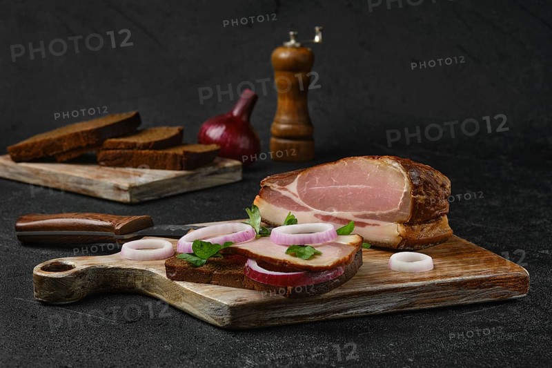 Rural sandwich with smoked bacon with brown bread on wooden cutting board