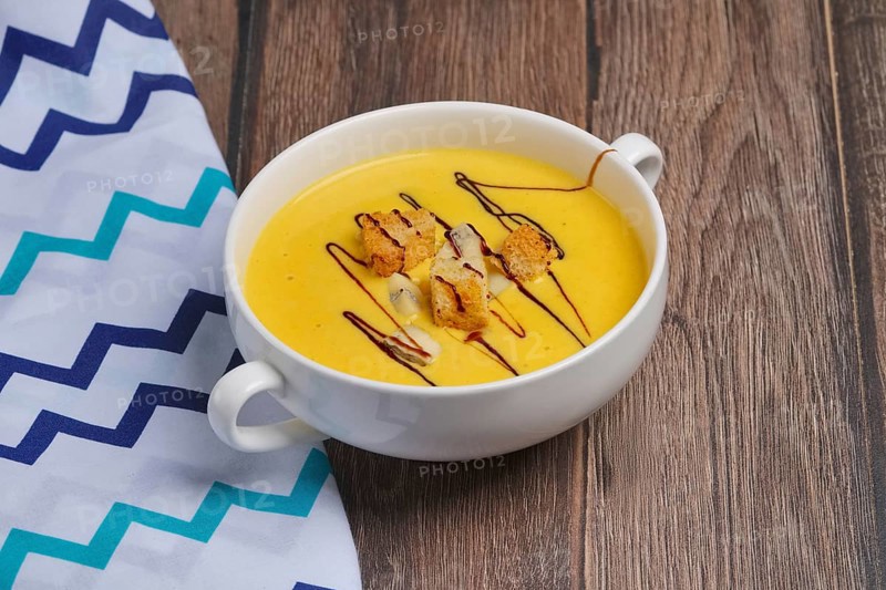 Plate of pumpkin soup on wooden table