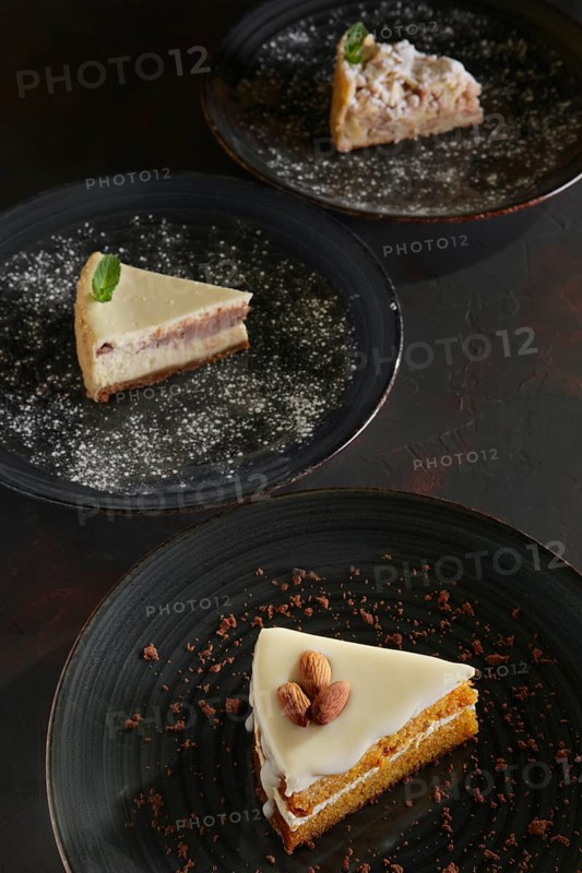 Three pieces of homemade cakes on a dark wooden vintage background