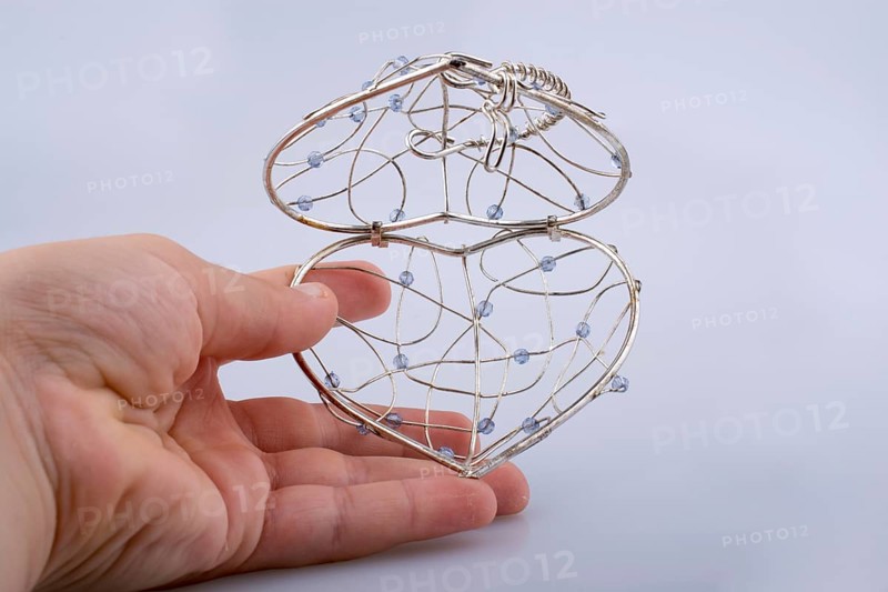 Heart shaped silver color metal wire cage in hand