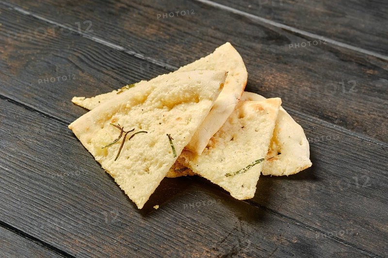 Four pieces of focaccia with herbs on wooden table
