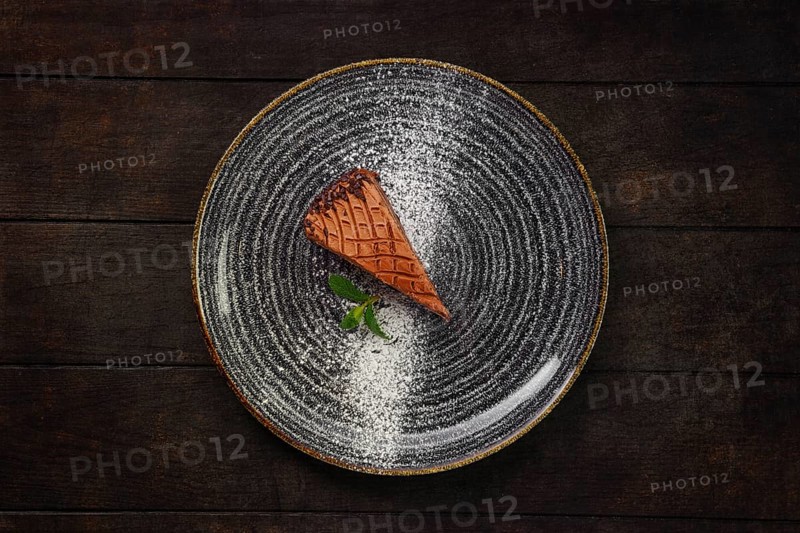 Top view of plate with piece of chocolate cake on wooden background