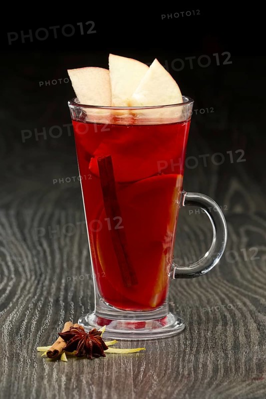Glass of hot fruit tea with apple and anise on wooden table
