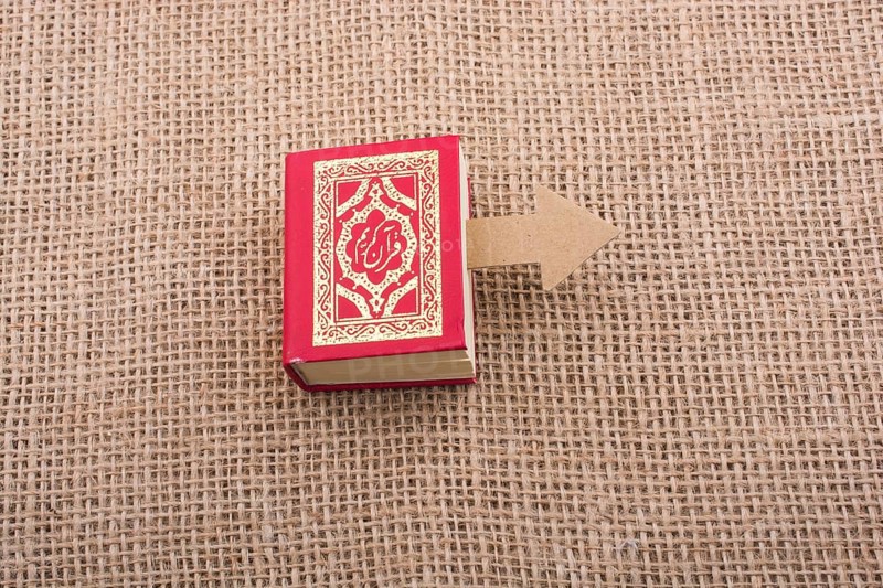 Paper arrow and Islamic Holy Book Quran in mini size
