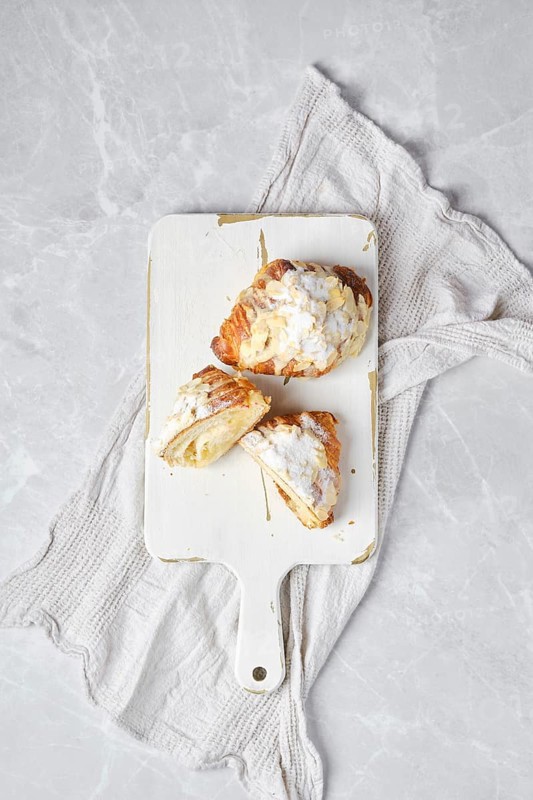 Top view of fresh croissant with caramel and peanut shavings on wooden serving board