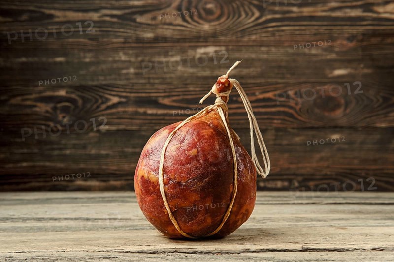 Round fermented beef sausage on wooden table